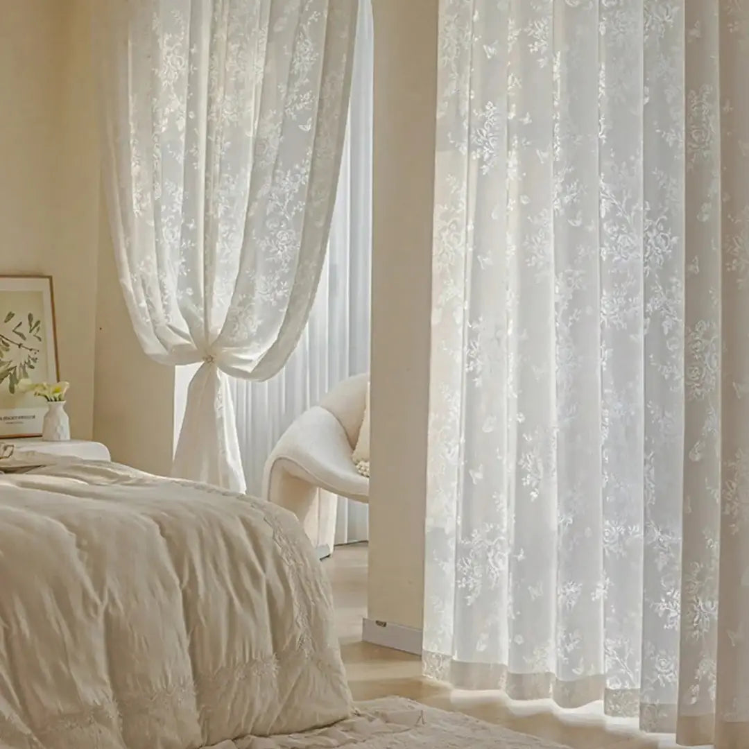 Cortina Delicate Bloom bege instalada em quarto claro, com painéis florais diante da janela