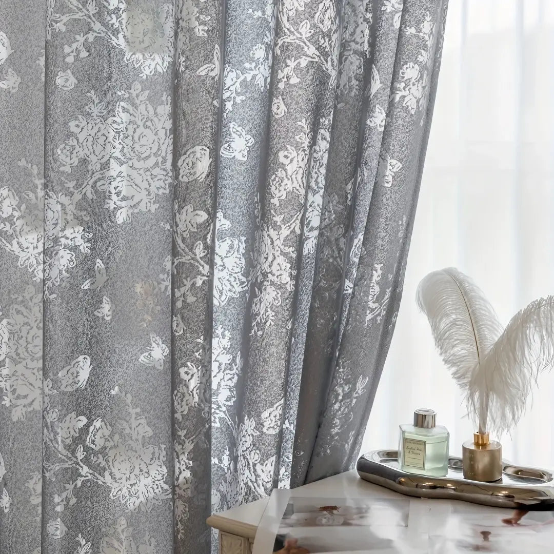 Pregas da cortina Delicate Bloom cinza em close, com ramos e flores brancos distribuídos no tecido