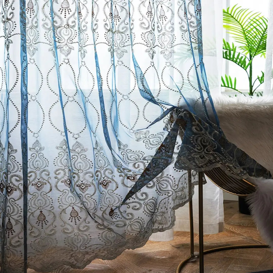 Painel azul da Éclat D'Or esvoaçando sobre cadeira, com bordado ornamental e barra recortada