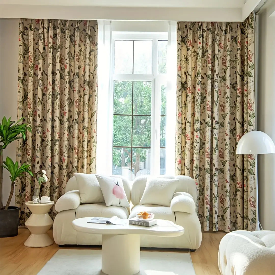Cortina Floral Rosê em composição ampla de sala, aberta ao centro atrás de sofá e mesa brancos