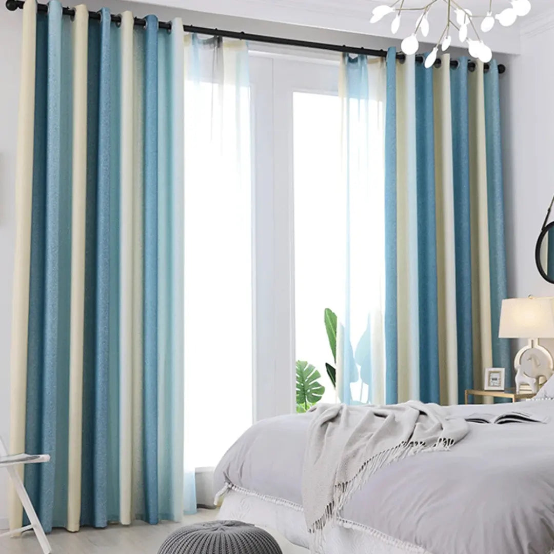 Cortina Aurora Luxe com listras azuis e claras instalada junto a uma janela de quarto