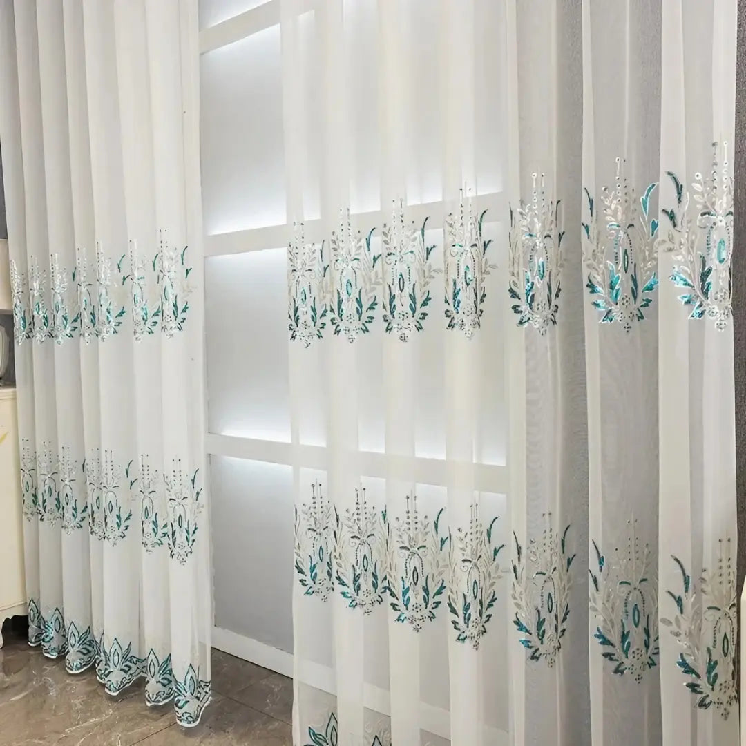 Painéis Éléonore brancos diante da janela, com duas faixas de bordados botânicos azul-turquesa
