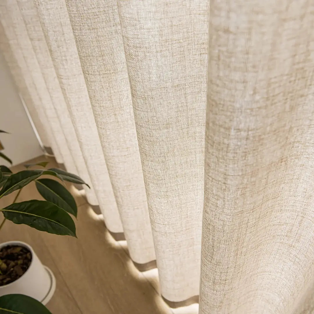 Barra da cortina Élysée próxima a plantas, com pregas leves e textura de fios aparentes